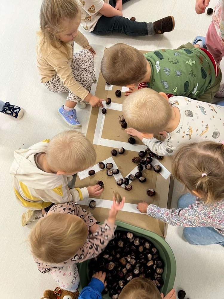 Maluchy układają kasztany i szyszki na trasie z taśmy – zajęcia sensoryczne