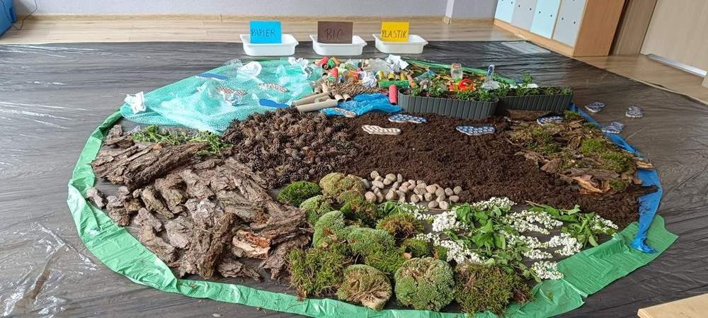 Ekologiczna makieta z mchu, kory, ziemi i odpadów do segregacji – papier, bio, plastik